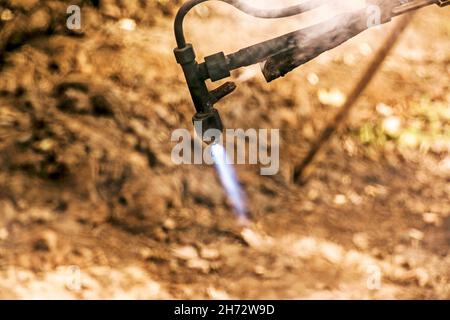 Close-up of the hand of an industrial worker working on the process of cutting rails. A male worker cuts steel using a plasma cutter. Stock Photo