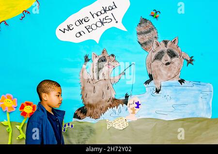 An African-American student walks past a poster in an elementary school promoting reading, March 30, 2012, in Columbus, Mississippi. Stock Photo