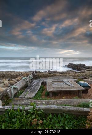 isle of wight shoreline at steephill cove, table and chairs made from driftwood on the beach at steephill cove on the isle of wight coastline, moody. Stock Photo