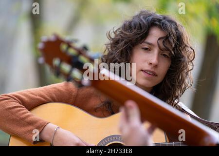 Young woman learning to play acoustic guitar in the park with a teacher Stock Photo