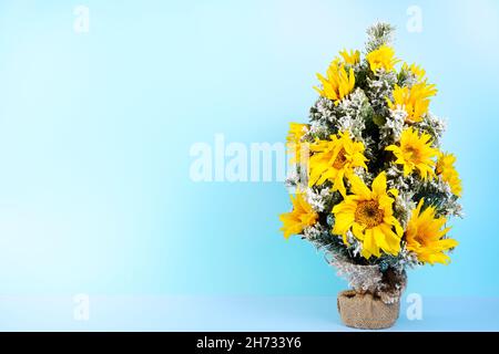 Christmas little three decorated with the snowflakes and fresh sunflowers ,isolated on a blue background Stock Photo