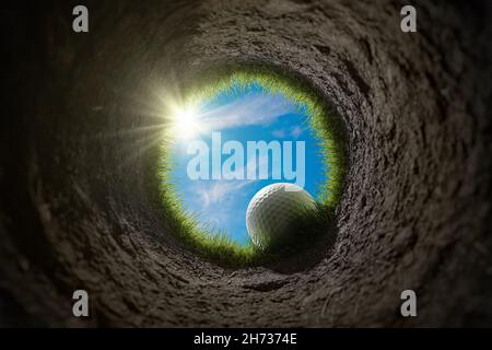 Golf ball is falling into hole. View from inside of hole. 3D rendered illustration. Stock Photo