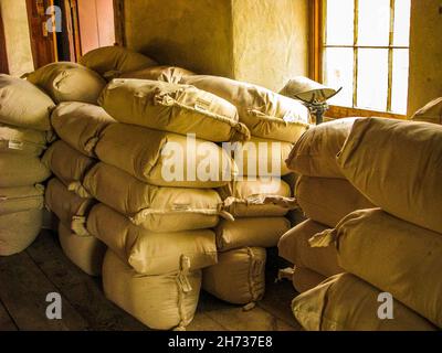 Flour sacks stacked in rows with light streaming through window, in J. Bellamy Flour Mill, Upper Canada Village, Ontario, Canada. Stock Photo