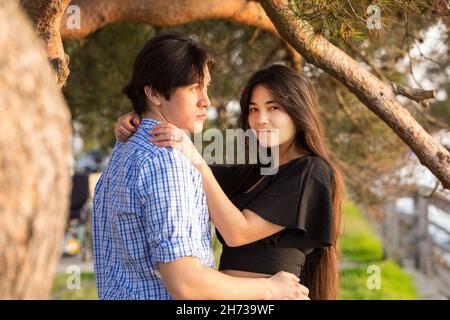 Goodlooking young biracial Asian Caucasian mixed race couple enjoying time together by lake at sunset in Pacific Northwest Stock Photo