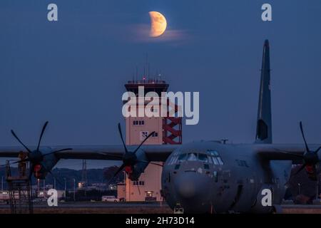 A crew chief assigned to the 374th Aircraft Maintenance Squadron maintains a C-130J Super Hercules under a partial lunar eclipse at Yokota Air Base, Japan, Nov. 19, 2021. On November 19, 2021, the Moon passes into the shadow of the Earth, creating a partial lunar eclipse so deep that it can reasonably be called almost total. (U.S. Air Force photo by Yasuo Osakabe) Stock Photo