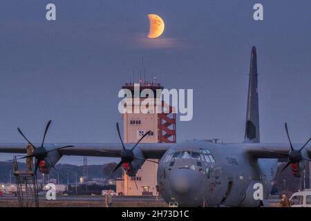 Crew chiefs assigned to the 374th Aircraft Maintenance Squadron maintains a C-130J Super Hercules under a partial lunar eclipse at Yokota Air Base, Japan, Nov. 19, 2021. On November 19, 2021, the Moon passes into the shadow of the Earth, creating a partial lunar eclipse so deep that it can reasonably be called almost total. (U.S. Air Force photo by Yasuo Osakabe) Stock Photo