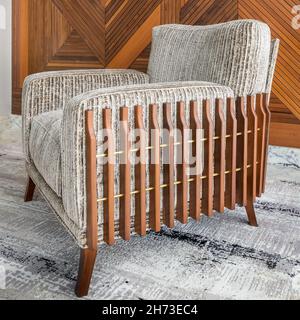 Modern beige armchair, and white contemporary carpet, over background of wood cladding wall Stock Photo
