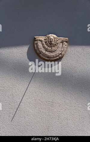 Sundial mounted on a wall casting a shadow during late afternoon sunlight, France Stock Photo