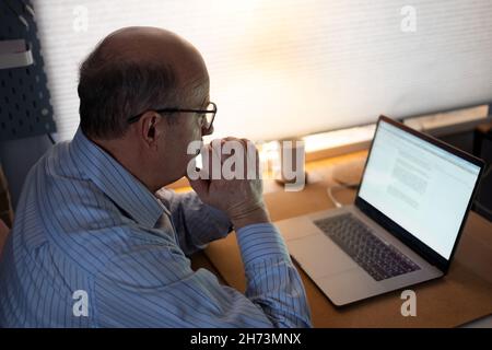 Senior man working with laptop computer at home and thinking on document. Stock Photo