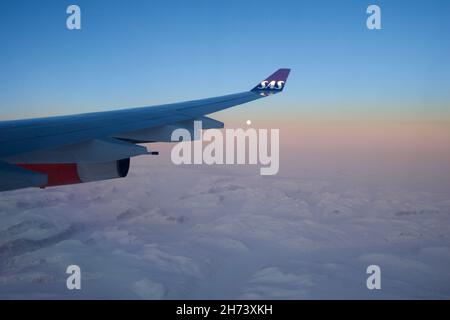 KOPENHAGEN, DENMARK - 24 NOV 2018: View from the aircraft cabin to the wing at sunset over the icebergs of Greenland Stock Photo