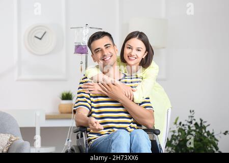 Young man in wheelchair on IV and his wife at home Stock Photo