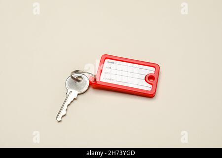 Key with red plastic tag on beige background Stock Photo