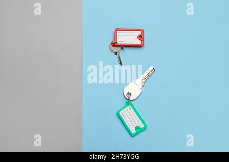 Keys with plastic tags on blue and grey background, top view Stock Photo