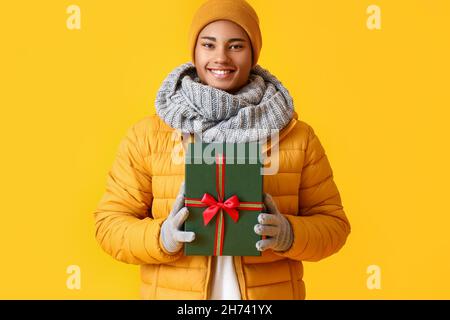 African-American man with Christmas gift on color background Stock Photo