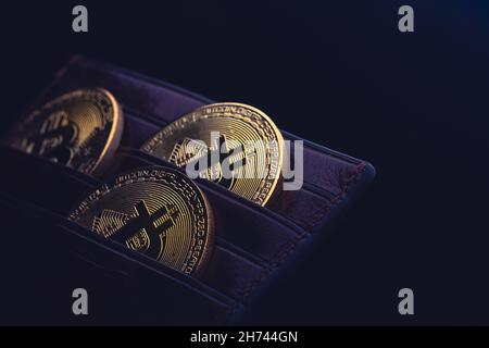 side view closeup concept of bitcoin cryptocurrency golden coins in leather black money wallet Stock Photo