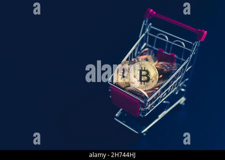 side view closeup cryptocurrency concept of market shopping cart full of bitcoin golden crypto coins on dark black background Stock Photo