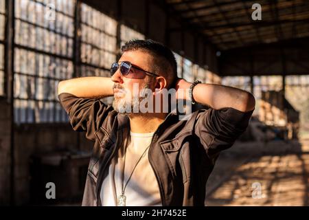 Male worker wearing sunglasses, enjoying sun rays in a factory plant. Stock Photo