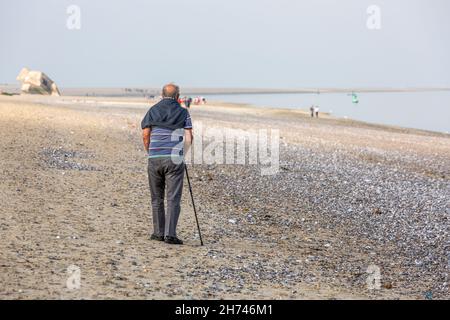 Elderly man walking with his cane on Hourdel beach. Bay of Somme, France Stock Photo