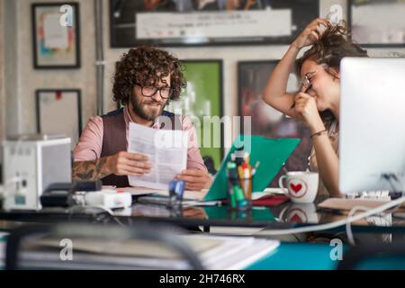 caucasian young male and  female working together, having fun. Stock Photo