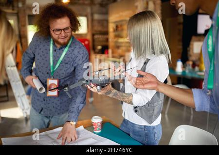 A group of young creative colleagues in a working atmosphere in the office is analyzing a drone they will use in a project Stock Photo
