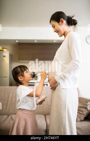 Little girl examining her pregnant mother with fetal heart Stock Photo