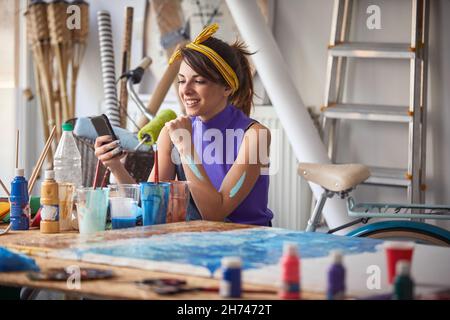 Young female artist using mobile in  art studio Stock Photo