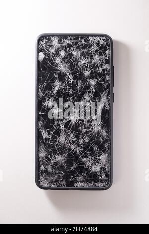 Modern touch screen smartphone with broken screen full of cracks on white background. Repair gadget concept Stock Photo