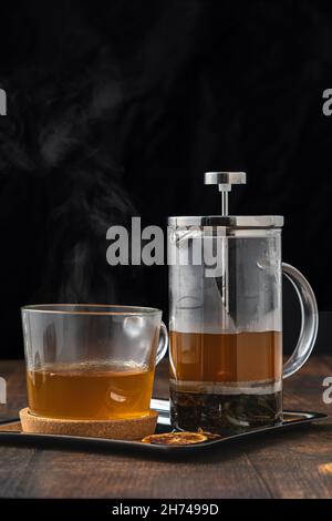 Hot winter tea served with a french press on a wooden floor. Stock Photo