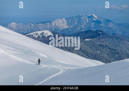 Man with backpack trekking in mountains. Cold weather, snow on hills. Winter hiking in the Carpathians. Stock Photo