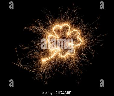 golden bright sparkler four leaf clover shape happiness shaped symbol isolated on dark black background. silvester new year birthday wedding and celeb Stock Photo
