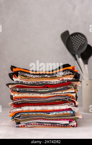 Various natural kitchen napkins in a stack close-up, in the background kitchen utensils in a concrete vase Stock Photo