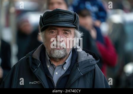 18-11-2021 Riga, Latvia Old generation. Portrait of positive senior bearded man in hat is standing outdoors and looking at camera Stock Photo