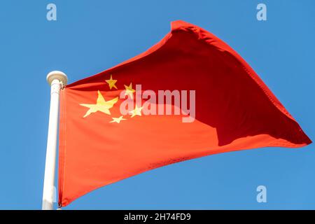 China Flag hanging and blowing in sunshine on blue sky background. Stock Photo