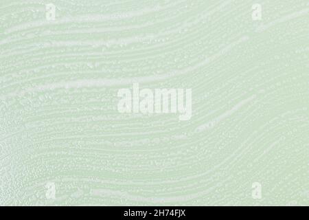 Abstract background with smeared soap foam on green backdrop, close-up Stock Photo