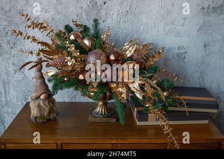Beautiful Christmas and New Year decoration with golden and bronze deco baubles and fir branches in vintage vase. Xmas decoration ideas. Winter holidays concept. Stock Photo
