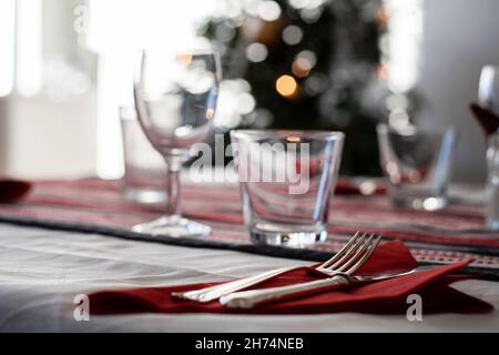 Elegant Christmas table setting with Christmas tree in the background. Stock Photo