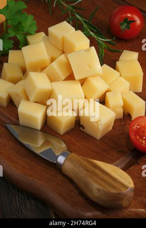 Close-up shot of cheese slices with knife on rustic wooden table Stock Photo