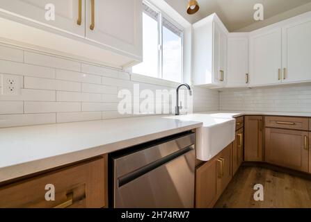 Kitchen sink with subway tiles backsplash, marble top with cabinets and dishwasher below Stock Photo