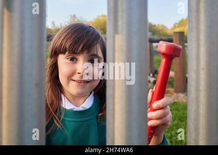 young girl with school unifome playing music on a xylophone in a playground Stock Photo