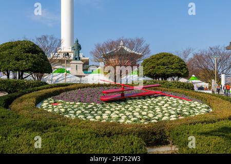 Busan, South Korea - November 28, 2015: Floral clock on background statue of Yi Sun-sin and Busan Tower. Stock Photo