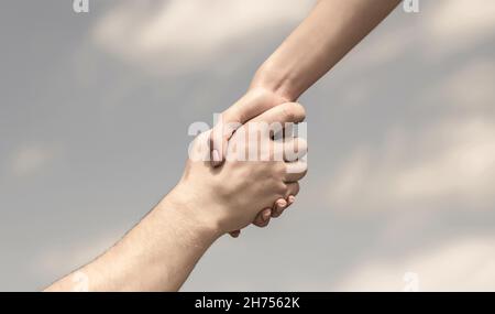 Hands of man and woman reaching to each other, support. Giving a helping hand. Lending a helping hand. Solidarity, compassion, and charity, rescue Stock Photo