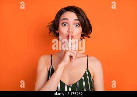 Photo of young girl finger cover lips shh keep secret confidential private isolated over orange color background Stock Photo
