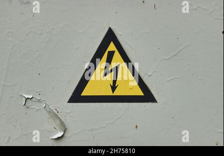 Close up of old Grey Hinged Power Supply Box with yellow danger warning sign electricity in remote places damaged Stock Photo