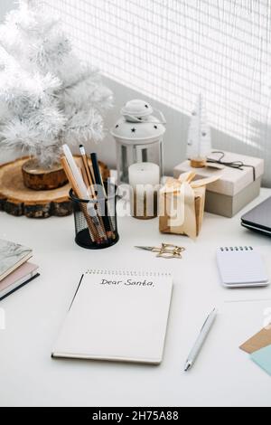 Wishlist, Modern Letters to Santa Claus from kids and adults. Handwritten Text Dear Santa in open notepad on the table. Paper and pencil ready to Stock Photo
