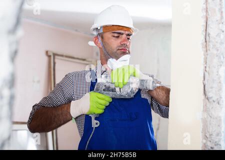 Adult man builder renovating with drill in gloves Stock Photo