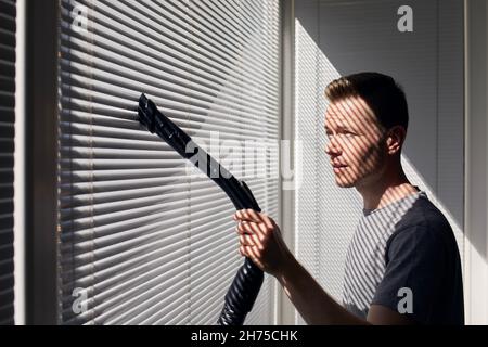 Man removing dirt from glass with squeegee. View of blue sky