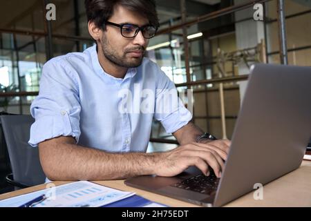 Young Indian business man using laptop computer working in office. Stock Photo