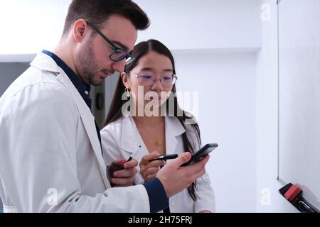 Two researchers in lab coat searching for information on the smartphone. Stock Photo