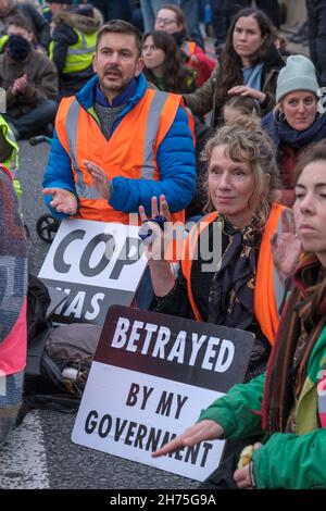 London, UK. 20th Nov 2021. People sit blocking Lambeth Bridge in solidarity with the peaceful protesters from Insulate Britain jailed for breaking an injunction and protesting on the roads in an attempt to force the government to insulate homes as a vital contribution to combating climate change. Many hold posters 'Betrayed By My Government'. Peter Marshall/Alamy Live News Stock Photo