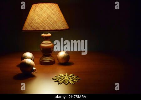 Christmas and New Year interior. Soft dim light from lampshade.  Christmas toys  on wooden table. Holiday Concept. Selective focus. Copy space. Stock Photo